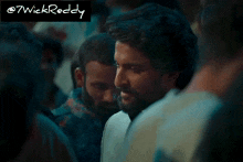 a man with a beard is standing in a crowd with a caption that says @7wickreddy