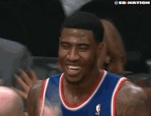 a basketball player in a blue , red , and white jersey is smiling .