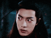 a close up of a man 's face with long hair and red eyes .