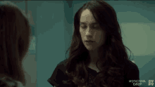 a woman with long red hair is talking to another woman in a room .