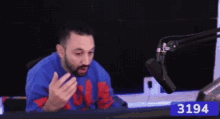 a man is sitting in front of a microphone with the number 3194 on the bottom
