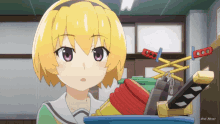a yellow haired anime girl is standing next to a bucket of toys
