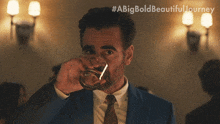 a man in a suit and tie is drinking from a glass with a big bold beautiful journey written on the bottom