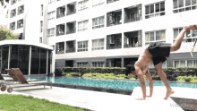 a man is doing a handstand in front of a building and a pool