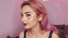 a woman with pink hair has a tattoo on her forehead