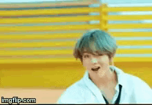a man in a white shirt and tie is making a funny face in front of a yellow wall .