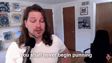a man with long hair is talking into a microphone with the words you shall never begin punning below him