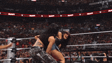 two women are fighting in a wrestling ring with a crowd watching and a sign that says raw on it
