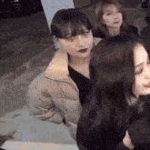 three women are sitting next to each other on a sidewalk .