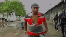 a man wearing a hat and a red shirt is walking down a street