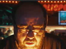 a man with glasses and a beard stands in front of a sign that says ' lis ' on it