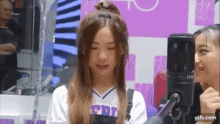 a girl is standing in front of a microphone with her eyes closed and smiling .
