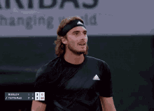 a man wearing an adidas headband and a black shirt smiles