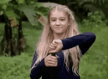 a young girl is holding a stick in her hand and giving a thumbs down .