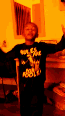 a young boy wearing a black shirt that says rules are for fools
