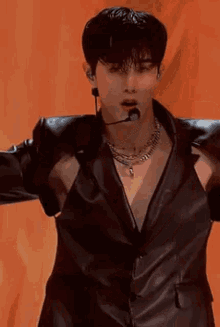 a man wearing a leather jacket and a necklace is singing into a microphone on a stage .