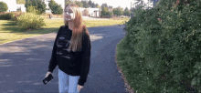 a woman wearing a black sweater with the number 7 on it stands on a path