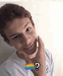 a young boy with a rainbow flag and a question mark on his arm is smiling .