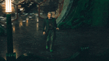 a man in a green coat and green shoes is standing in a dark room