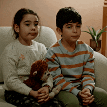 a boy and a girl sitting on a couch with a stuffed monkey