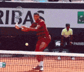 a man swings a tennis racquet in front of an ad for ribas