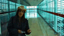 a woman in a cowboy hat stands in a hallway