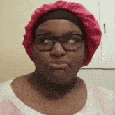 a woman wearing glasses and a pink hat makes a face