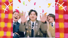 a group of people are standing in front of a pink and yellow checkered background with confetti falling around them
