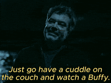 a man in a dark room with the words just go have a cuddle on the couch and watch a buffy below him