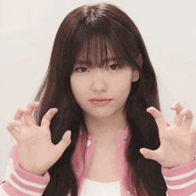 a girl with long hair and bangs is wearing a pink and white jacket