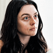 a woman with long black hair looks at the camera
