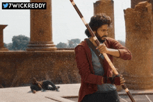 a man holding a stick in front of a sign that says 7wickreddy on it