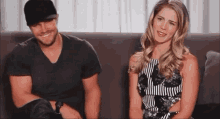 a man and a woman are sitting next to each other on a couch and smiling