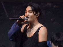 a woman is singing into a microphone on a stage while another woman looks on .