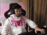 a man is sitting in a chair wearing headphones and a spider man sweatshirt .