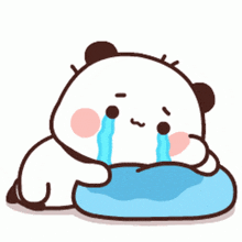 a cartoon panda bear is crying while laying on a blue pillow .