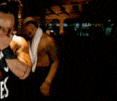 a shirtless man with a towel around his neck is standing in a dark room .