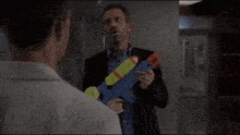 a man in a suit is holding a water gun in his hand