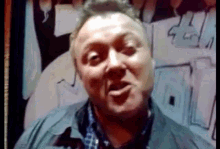 a man in a blue jacket is making a funny face in front of a drawing of a man