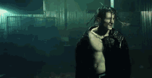 a man without a shirt is standing in a dark room smoking a cigarette