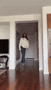 a man in a white sweater is dancing in a hallway