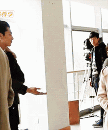 a group of people are standing in a room with a sign that says ' exit ' on it