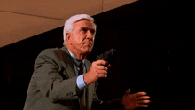 a man in a suit and tie is holding a gun that is shooting a flame .