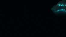 a man in a suit stands in a dark room with a light shining on him