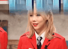a woman in a red jacket and tie is talking to someone .