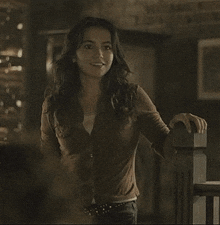 a woman in a brown shirt is smiling while standing next to a railing