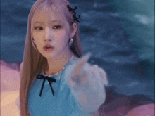a woman in a blue dress with a black bow pointing at the camera