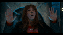 a woman in a red sweater says binary in front of a glass door