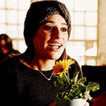 a woman holding a potted plant with a sunflower in it