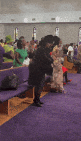 a group of people are sitting in a church with purple seats
